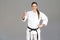 Positive athletic young woman in white kimono and black belt sta