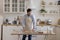 Positive baker man wearing apron rolling dough on floury table