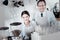 Positive baristas smiling and standing near the coffee machine