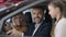 Positive bearded businessman sitting in car talking with woman and girl. Portrait of confident happy husband and father