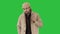 A positive bearded male dressed in a trench coat walking and talking on a green screen, chroma key.