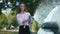 Positive beautiful woman spraying car wash shampoo with high pressure washer outdoors in slow motion. Portrait of young