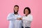 Positive black couple bumping fists, celebrating achievement or success, reaching common goal on pink studio background