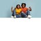 Positive black couple sitting on empty horizontal board for advertisement
