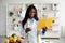 Positive black dietitian with notebook and glass of water, standing at clinic and smiling at camera, free space