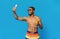 Positive black man in swimwear taking summer selfie on cellphone