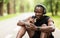 Positive black sportsman eating protein bar while resting