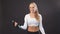 Positive blonde fitness woman lifting dumbbell weights