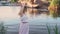 Positive blonde girl barefoot dancing on a stone by the river like a fabulous mermaid, her pink long gentle hipster