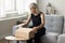 Positive blonde senior woman packing parcel for sending