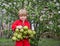 Positive boy in against a background of a blossoming apple tree holds a heavy eco bag full of organic green apples