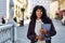 positive businesswoman standing on street holding folder with documents