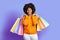 Positive carefree black woman shopaholic holding colorful bags purchases