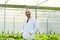 Positive caucasian male plant researcher, geneticist, biologist in white coat standing among vegetable in industrial