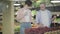 Positive Caucasian man and woman touching hands accidentally as taking strawberry from supermarket shelf. Portrait of