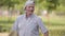 Positive caucasian senior man in white baseball cap dancing in the summer park. Middle-aged smiling person enjoying his