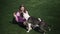 Positive charming woman in eyeglasses playing with American Staffordshire Terrier feeding pet with bagel. Wide shot