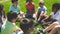 Positive children friends sitting on grass together and talking in park