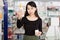 Positive chinese woman near counter chooses antibacterial at in pharmacy