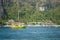 Positive, colored to Green and yellow passenger touristic speed boat, cruising near railay beach