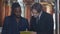 Positive confident African American brewer and Caucasian pub owner signing agreement shaking hands smiling. Handshake of