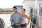 Positive couple filling up tank of their car with gasoline in gas station