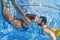 Positive couple swimming underwater in outdoor pool