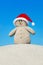 Positive creative sandy Snowman in red Santa hat at beach