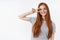 Positive cute optimistic redhead teenage girl have fun showing peace victory gesture hold disco sign eye tilting head