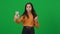 Positive cute teen girl talking at smartphone video chat pointing around on green screen. Portrait of satisfied African