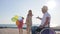 Positive disabled man, mom and daughter hopping with balloons in backlight, little girl and mother run to disabled