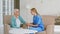 Positive doctor joins hands cheering up mature grey haired lady sitting in armchairs in stylish office