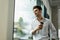 positive, dreamy businessman standing near window