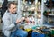 Positive elderly man choosing interesting souvenirs at traditional flea market