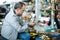 Positive elderly man choosing interesting souvenirs at traditional flea market