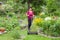 Positive elderly woman mowing grass with lawn mower in the garden