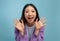 Positive emotions. Portrait of excited iasian lady screaming with joy and spreading hands, posing over blue background