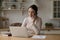 Positive engaged young freelance professional woman working in home kitchen