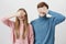 Positive european couple in knitted colourful sweaters posing against gray background. Fair-haired young male and female