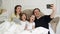 Positive Family Selfie with Mother, Father and Two Children Lying on the Bed and Wearing Pajamas. Handsome Man is Taking