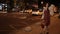 Positive fashionable woman walking on night street