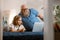 Positive father with beard and little girl take part in video conference via laptop on bed