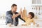 Positive father and little boy giving high five and smiling to each other, enjoying healthy breakfast at kitchen