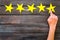 Positive feedback, good service concept. Hand touch the best star on dark wooden background top-down copy space