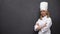 Positive female chef crossing hands on blackboard background, healthy nutrition