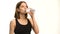 Positive female fitness model after workout drinking water in studio over white background.