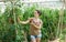 Positive female horticulturist standing near tomatoes seedlings