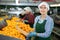 Positive female worker with box of mandarins at fruit sorting factory