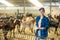 Positive female worker of livestock farm standing in goat stall