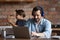 Positive freelance man in headphones working at laptop